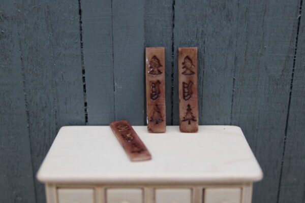 Miniatuur speculaasplank geschilderd schaal 1:12 met drie traditionele figuren, afmetingen 3 x 0,7 x 0,3 cm, perfect voor poppenhuizen en miniatuurcollecties.