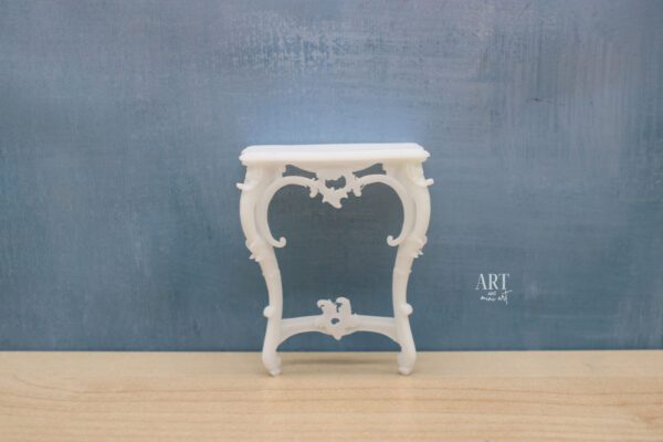 1:12 schaal Rococo-stijl tafel met sierlijke, gebogen poten en verfijnde details, afmetingen 3,2 cm x 5,7 cm x 7,2 cm hoog, geplaatst tegen een blauwe achtergrond.